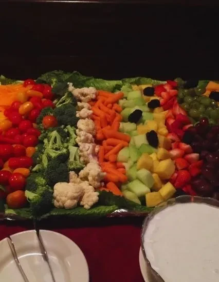 Vibrant buffet platter with colorful fruit and vegetable rows.