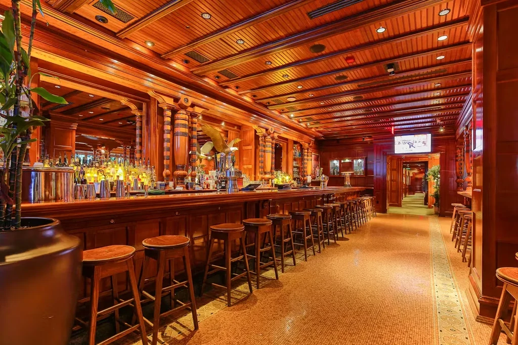 Empty, classic wood-paneled bar with liquor display and eagle sculpture.