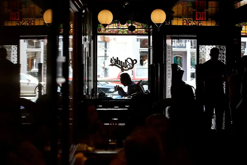 Backlit restaurant: dark wood, stained glass, silhouetted patrons, "Schulz's" sign.
