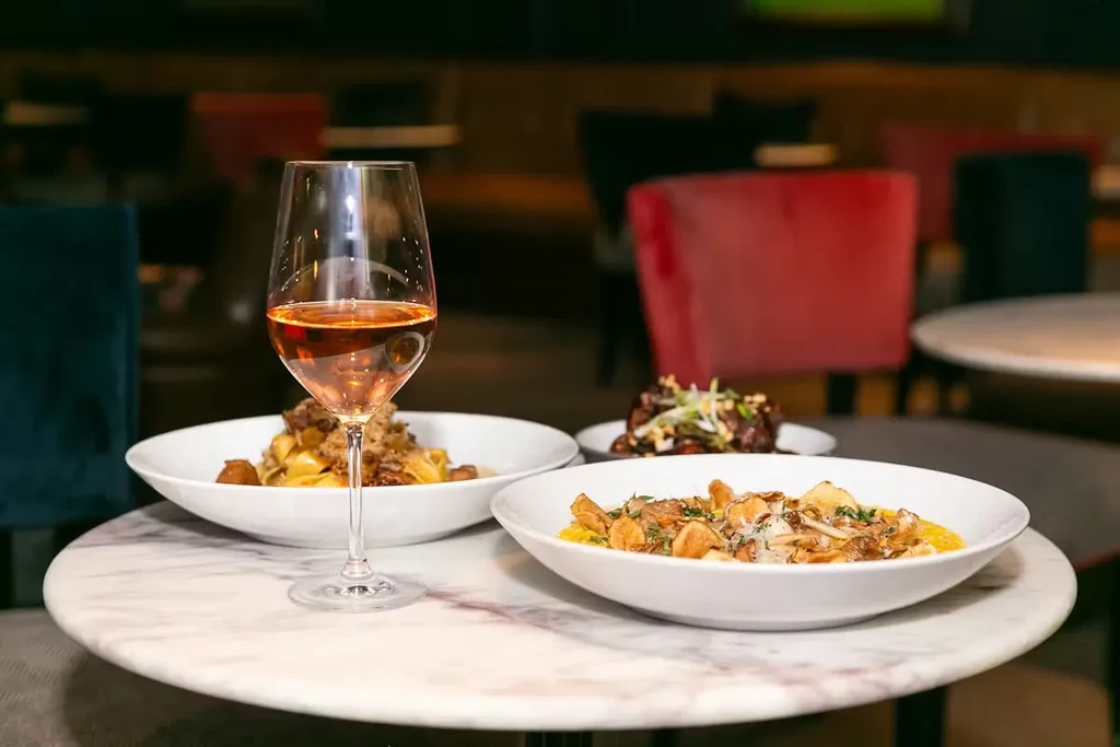 Close-up of three dishes and rosé wine on a restaurant table.