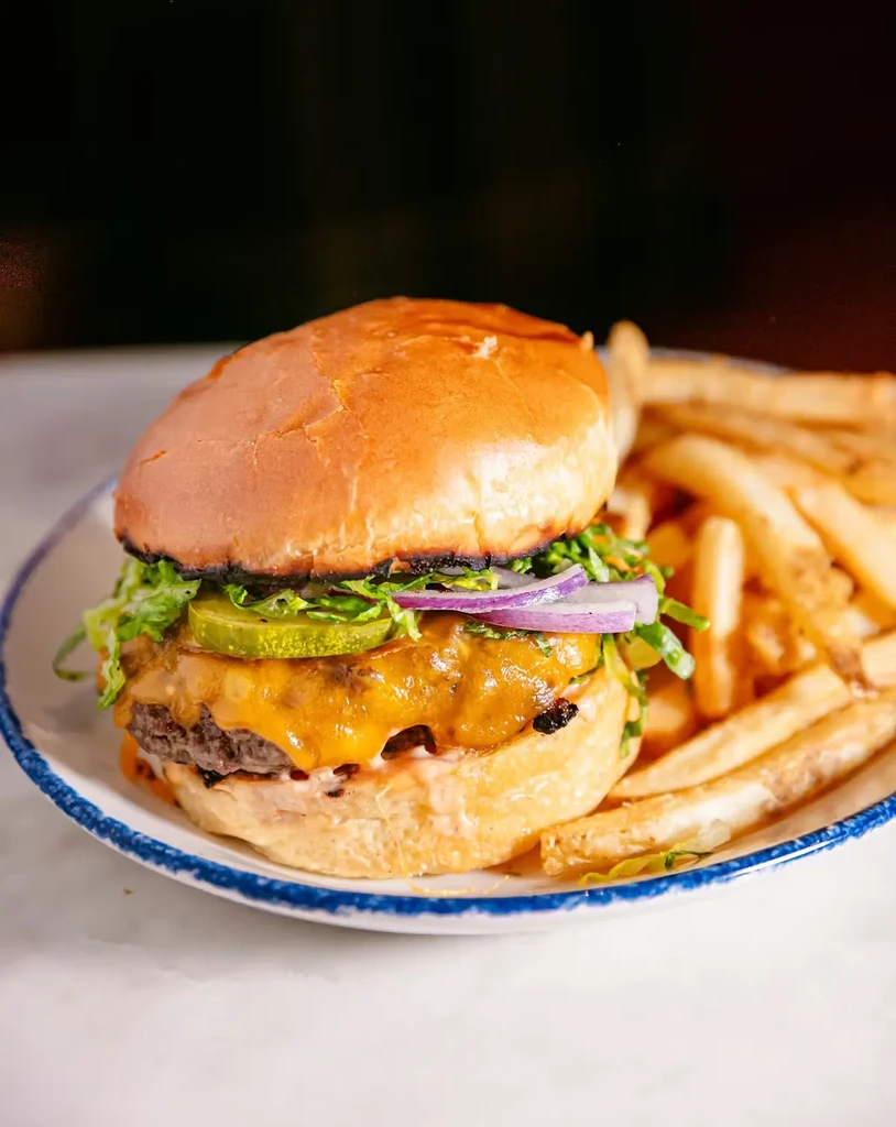 Hamburger with beef patty, cheese, lettuce, onion, pickles, and fries.