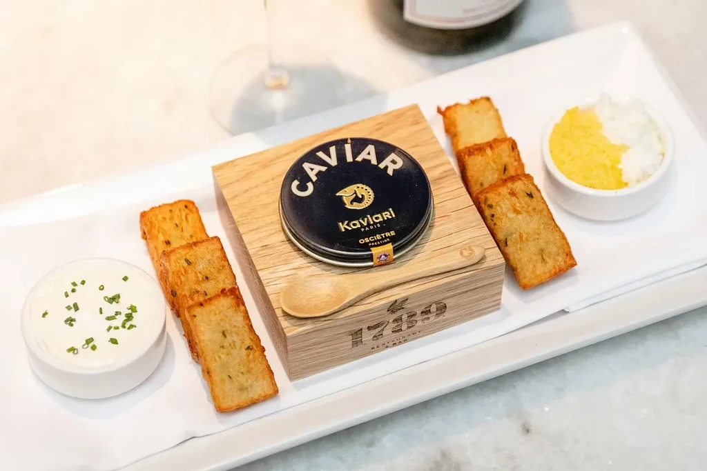 Kaviari Oscietre caviar tin with potatoes, sauce, and egg on a platter.