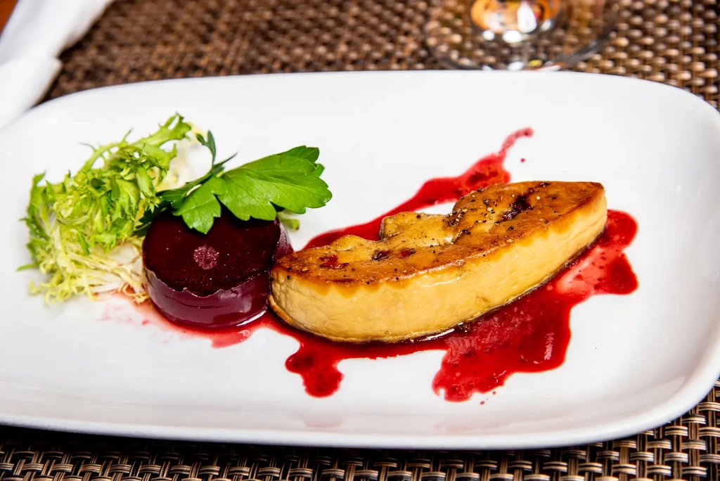 Gourmet pan-seared delicacy with red sauce, frisée, and parsley.