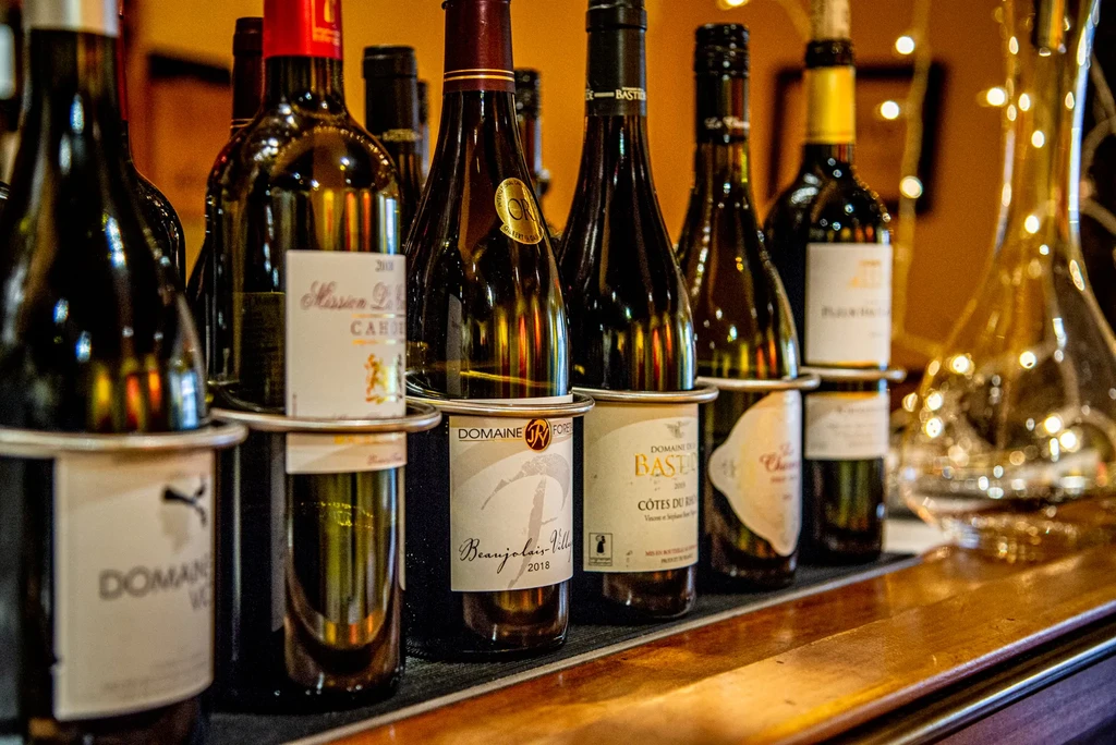 Various wine bottles and a decanter on a warmly lit bar.