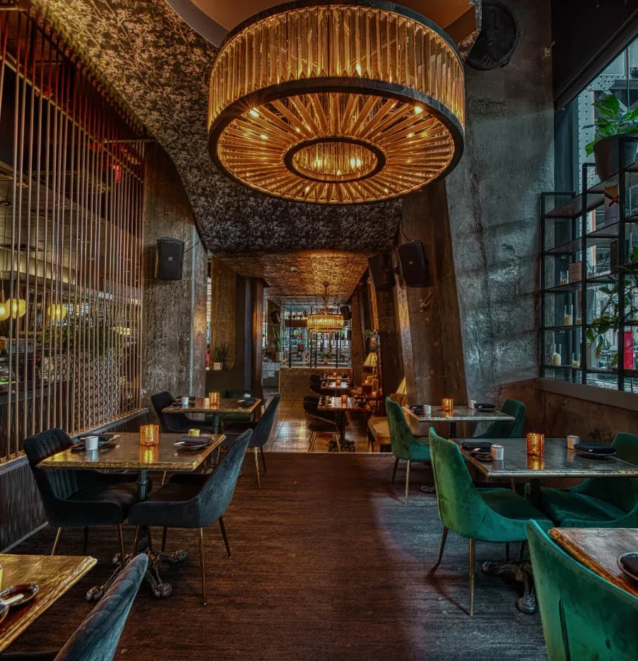 High-end restaurant interior with multi-tiered chandelier, velvet chairs, and dim lighting.