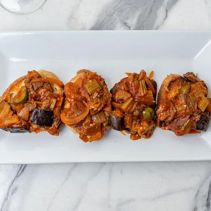 Four bruschetta topped with chunky vegetables and tomato mixture.