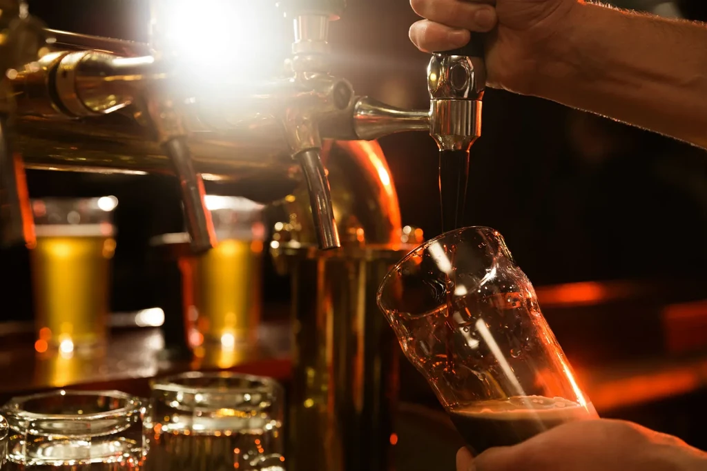 Close-up: Hand pouring dark beer from a tap into a glass.