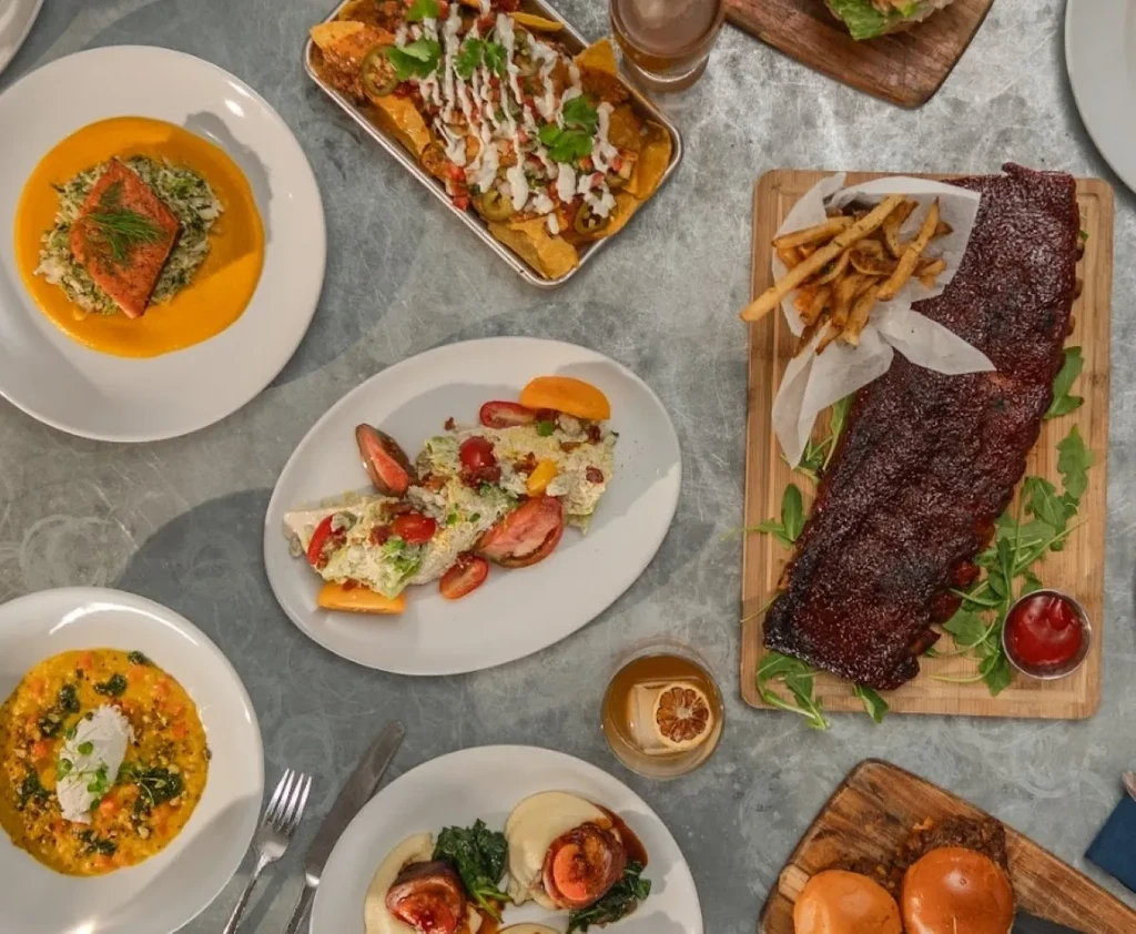 Overhead shot: various restaurant dishes including salmon, nachos, and ribs.