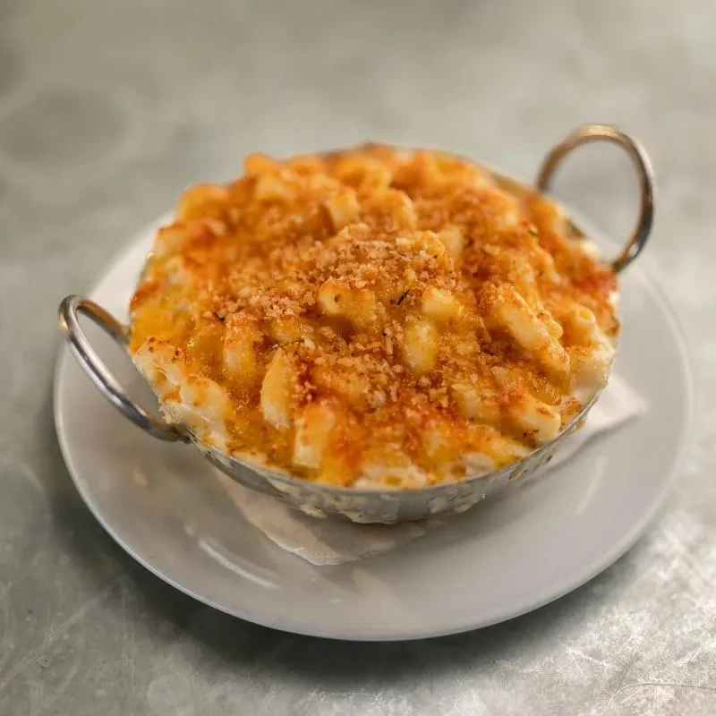Baked macaroni and cheese with toasted breadcrumbs in a metal dish.