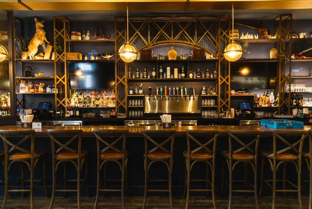 Empty, elegant bar with liquor-filled shelves, dark wood, and beer taps.