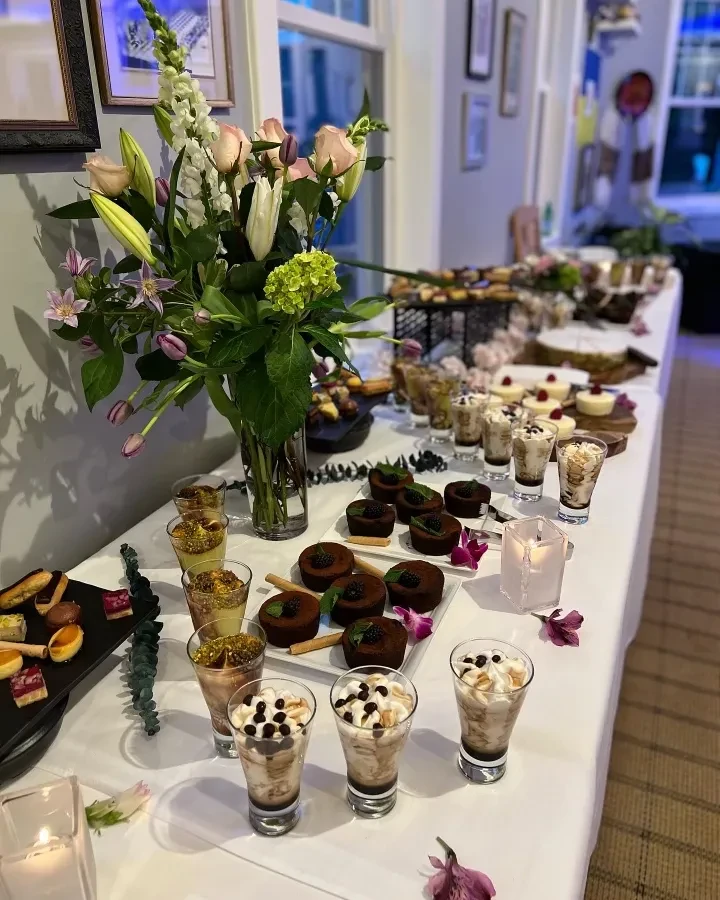 Sophisticated dessert buffet featuring a vibrant floral centerpiece and varied pastries.