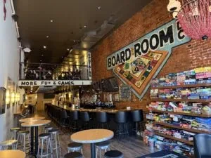 Board game bar interior with mural, shelves of games, and seating.