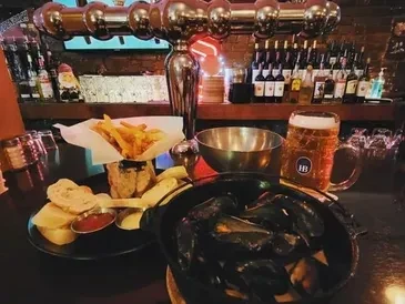 Mussels, fries, and a mug of beer on a cozy pub bar.