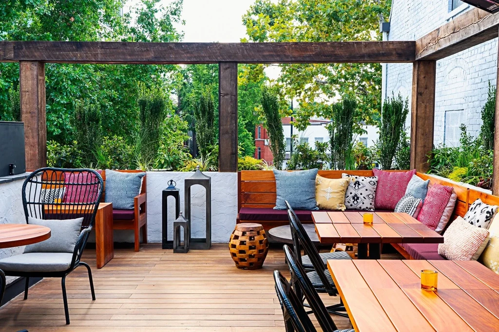 Outdoor patio with colorful pillows, wooden seating, and decorative lanterns.