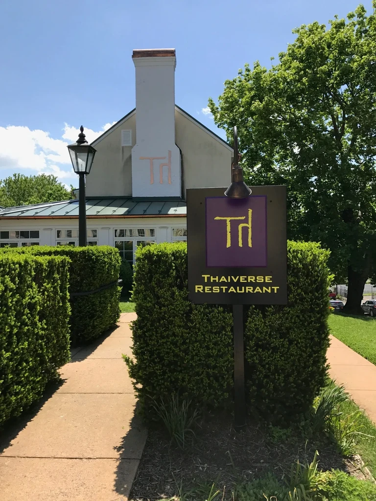 Sunny concrete path leading to THAIverse Restaurant with a prominent purple sign.