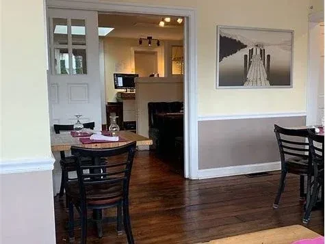 Empty restaurant interior with wooden tables, one set, two-toned walls, and artwork.