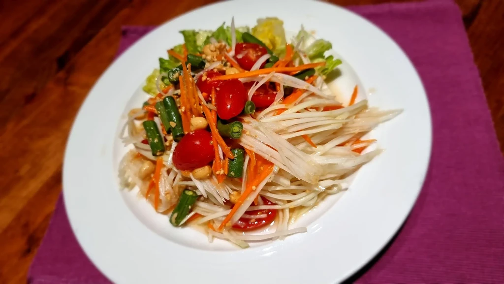Overhead shot: Colorful papaya salad with carrots, tomatoes, green beans, peanuts.