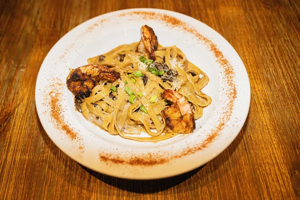 Creamy shrimp pasta dish with grated cheese and decorative spice rim.