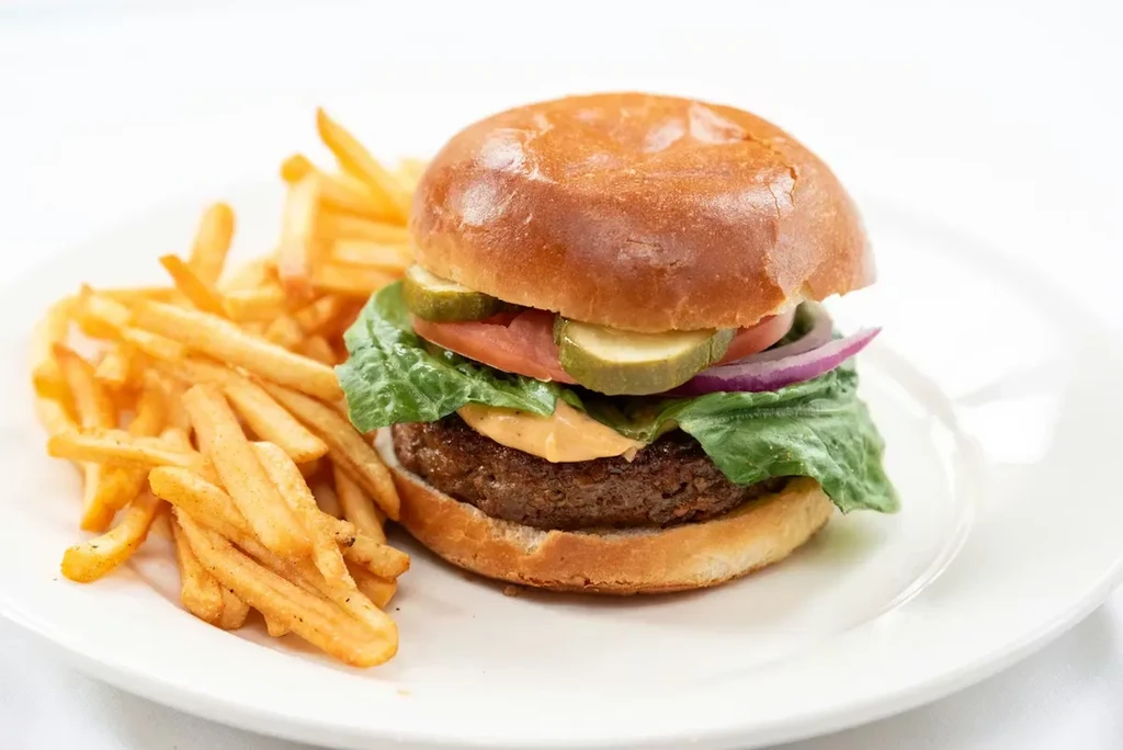 Hamburger with brioche bun, cheese, vegetables, and golden crispy fries.
