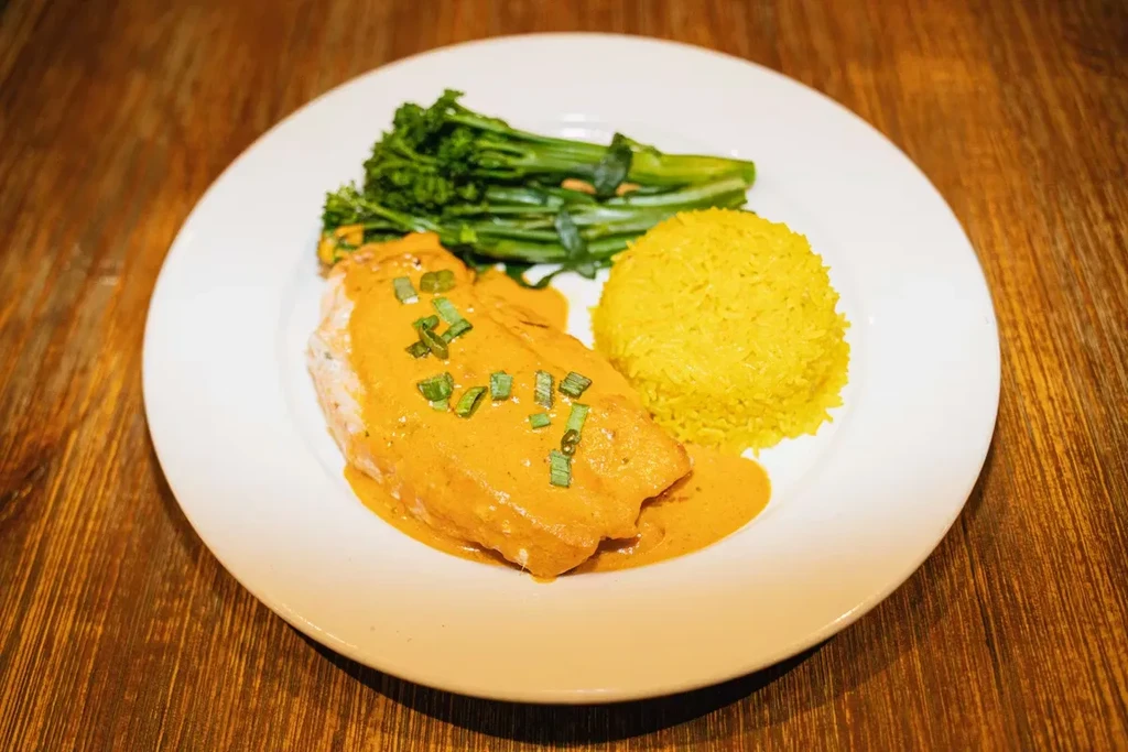 Plated meal: sauced fish or chicken, yellow rice, and green broccoli.