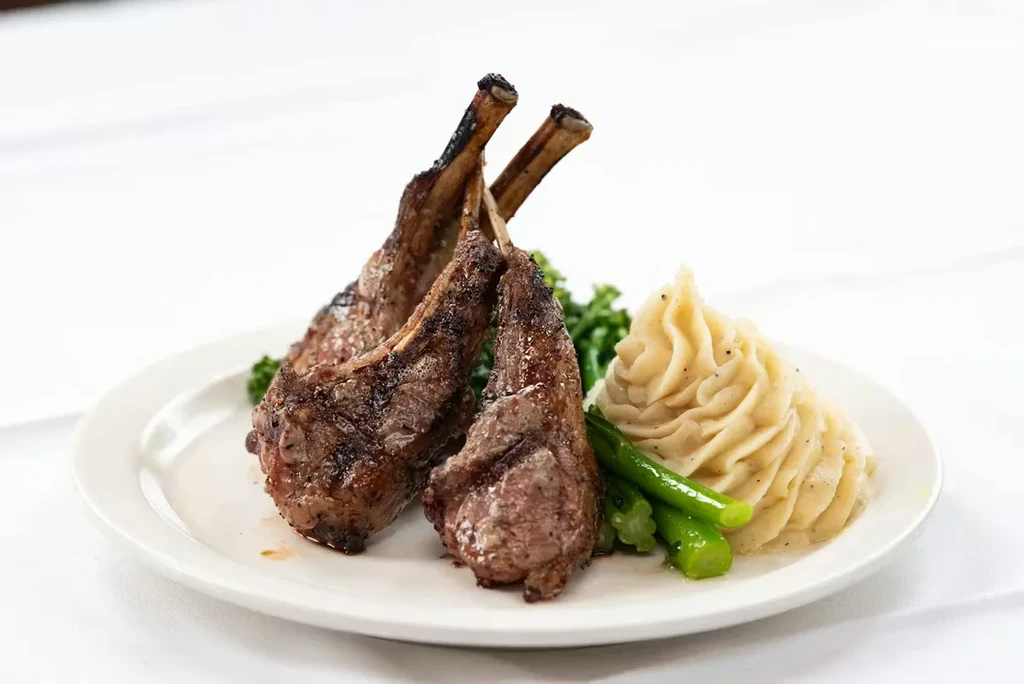 Finely plated lamb chops, asparagus, and mashed potatoes.