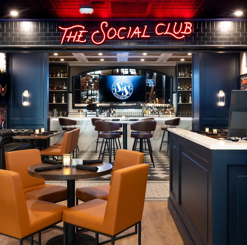 Modern restaurant and bar with "THE SOCIAL CLUB" neon sign, no people.