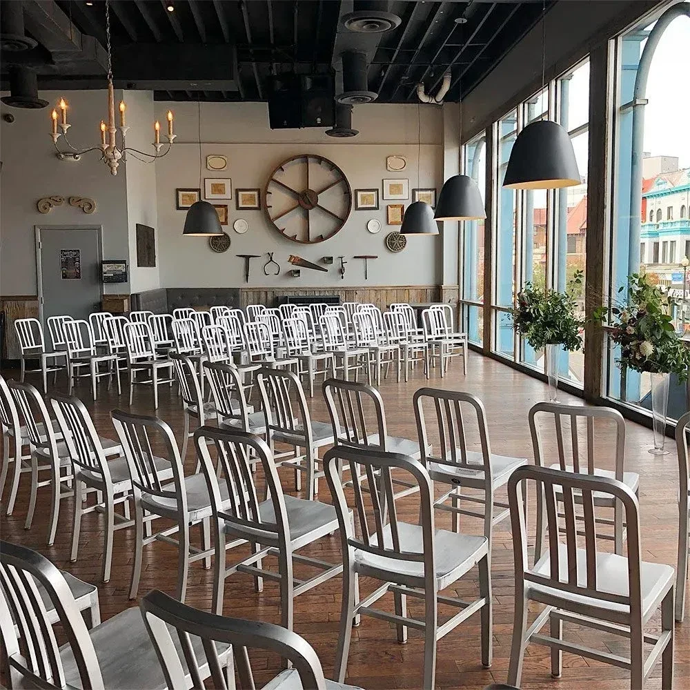 Industrial event space with rows of chairs, vintage tools, and arched windows.