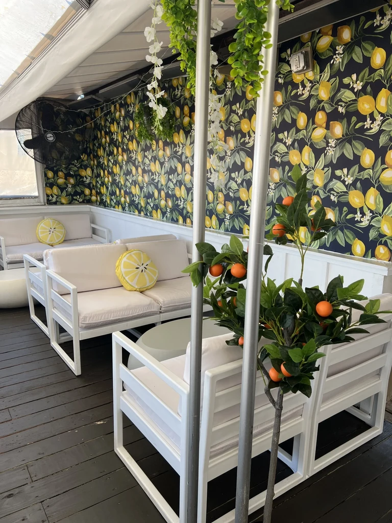 Mediterranean-inspired seating area with blue lemon wallpaper and white furniture.