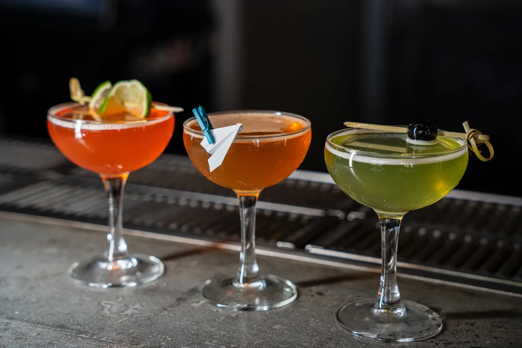 Three distinct cocktails in coupe glasses with unique garnishes.