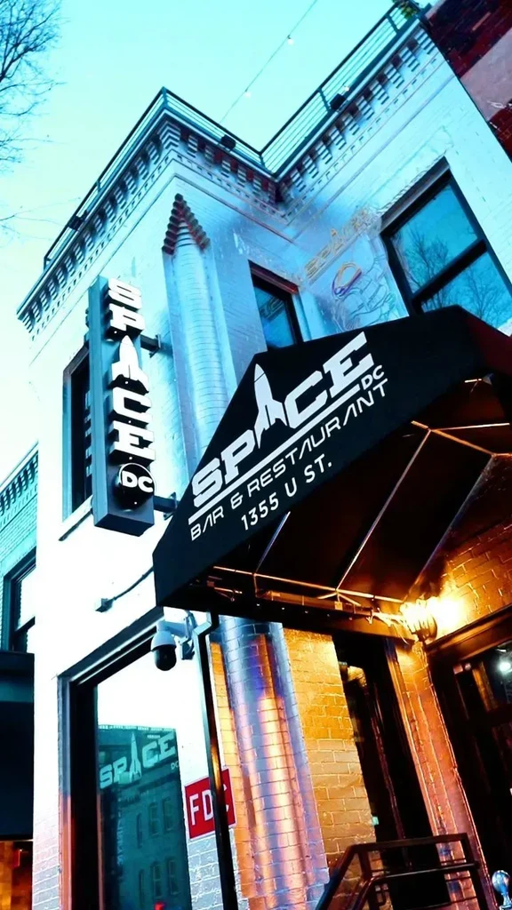 Old brick building of Space Bar & Restaurant DC, glowing blue.