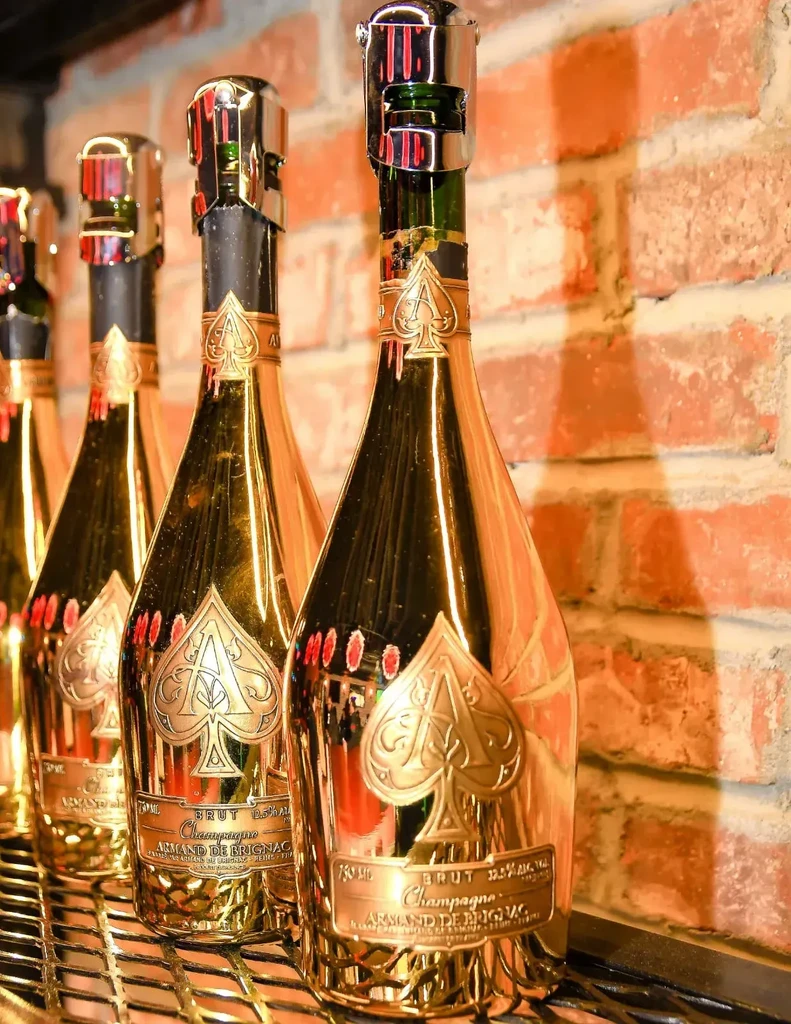 Three golden Armand de Brignac champagne bottles on a black grate.