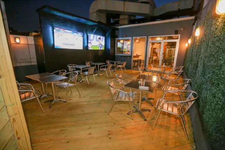 Empty rooftop patio with sports on TVs and string lights.