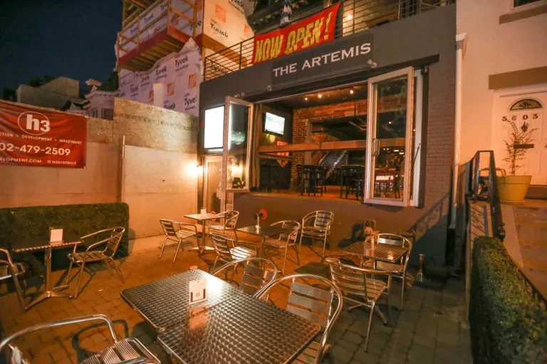 The Artemis restaurant exterior at night with empty patio and construction.