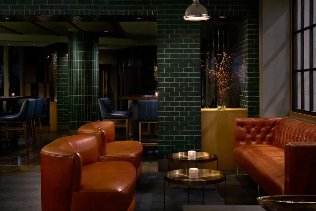 Restaurant lounge with orange leather seating, green tiled walls, dim light.
