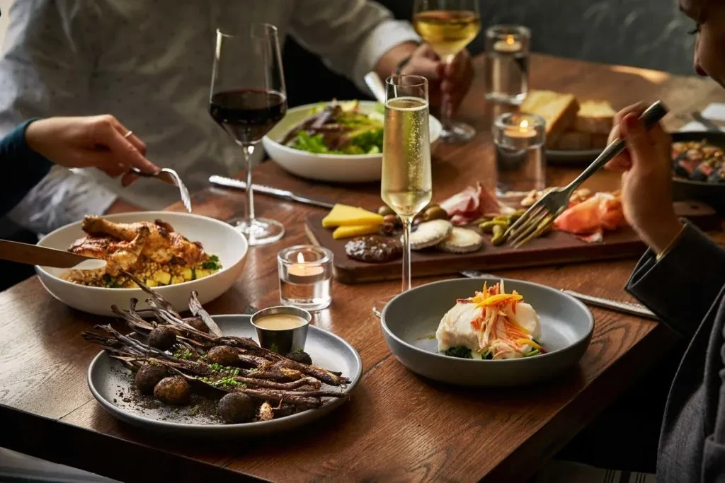 Upscale restaurant table with plated dishes, wine, candles, and diners.