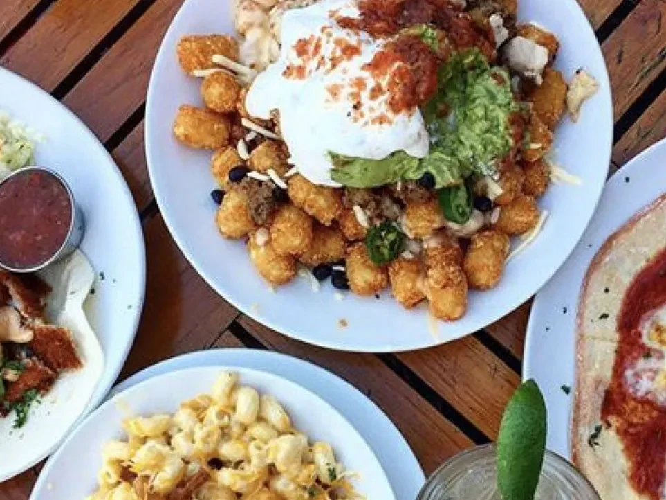 Loaded tater tots with sour cream, guacamole, meat, and jalapeños.