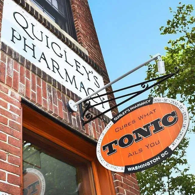 Signs for Quigley's Pharmacy and Tonic on a red brick wall.