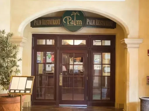 Arched entrance to Palm Restaurant with circular sign.