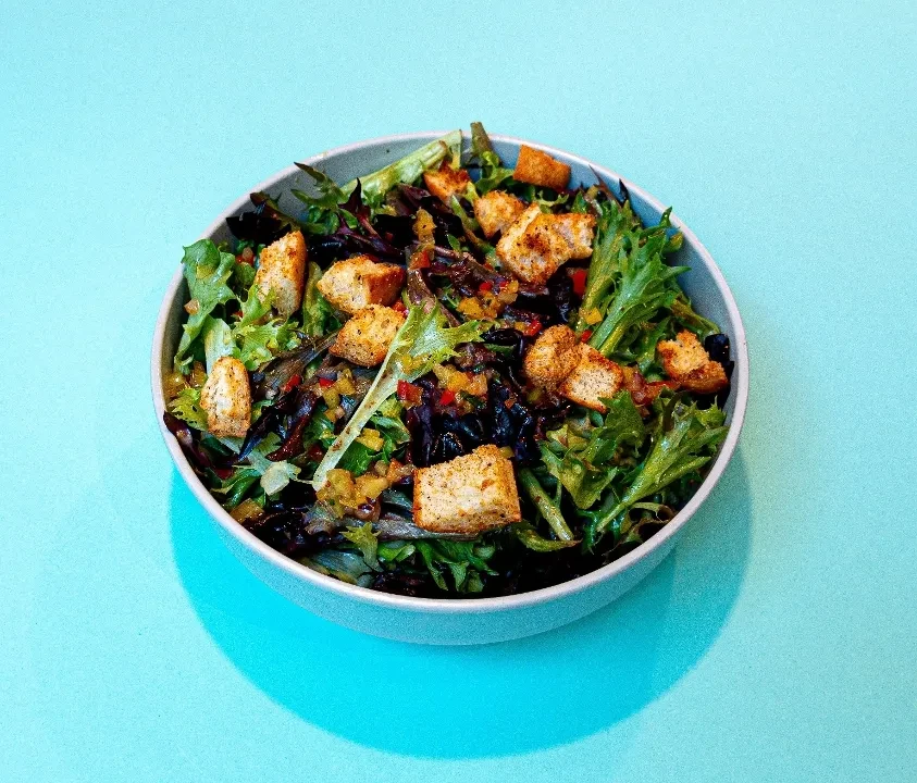 Vibrant green salad with crispy croutons and colorful relish in a bowl.