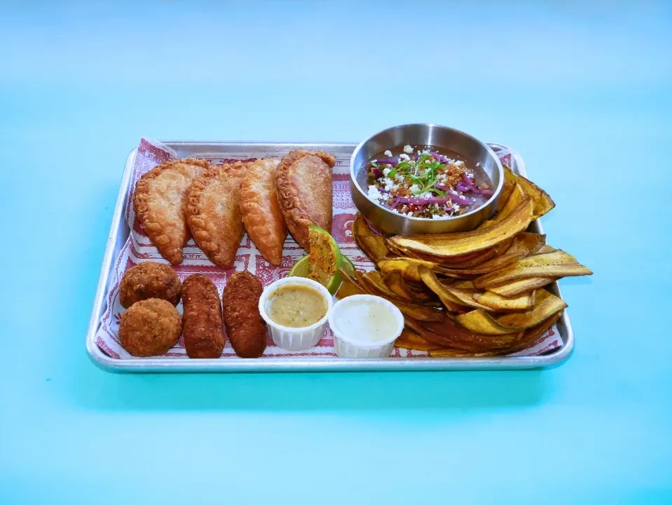 Silver tray with assorted fried appetizers, sauces, and plantain chips.