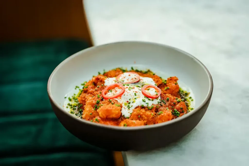 Orange-red pasta with cream, chili slices, chives, and red spice.