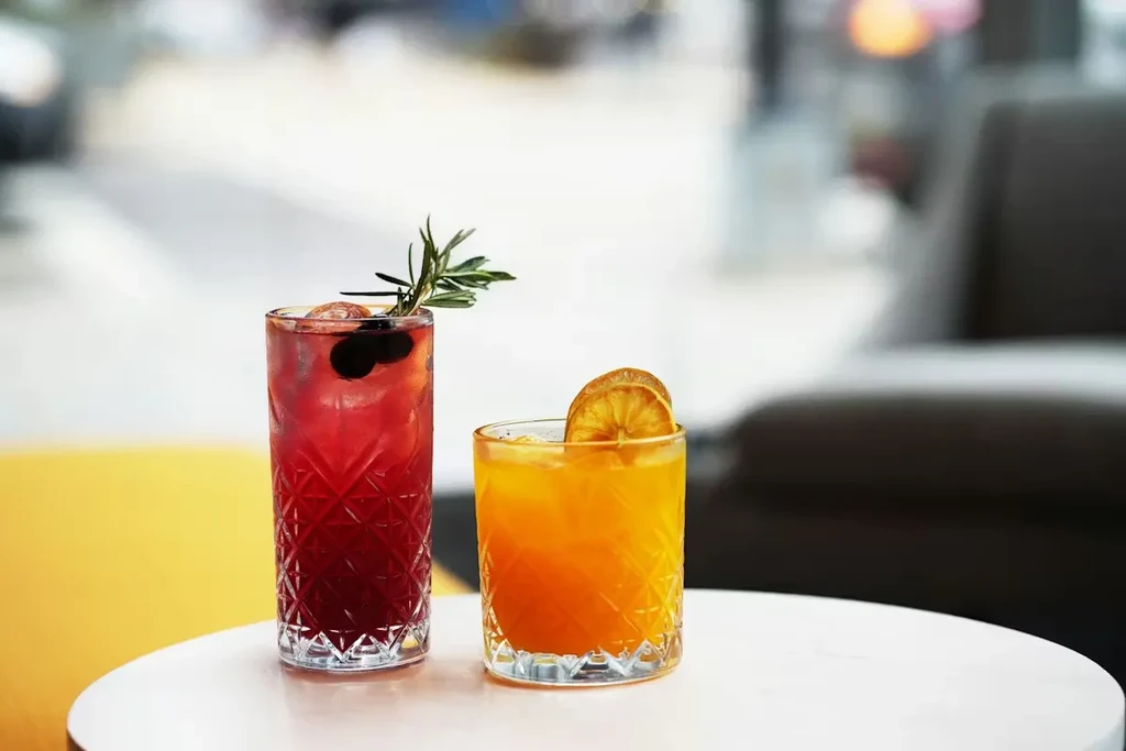 Two vibrant cocktails in etched glasses on a white table.