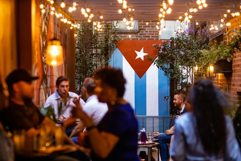 Night patio with string lights, plants, and a Cuban flag mural.