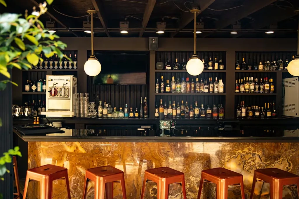 Upscale bar with amber counter, copper stools, and extensive liquor bottles.