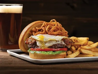 Burger with fried egg, onions, bacon, fries, and dark beer.