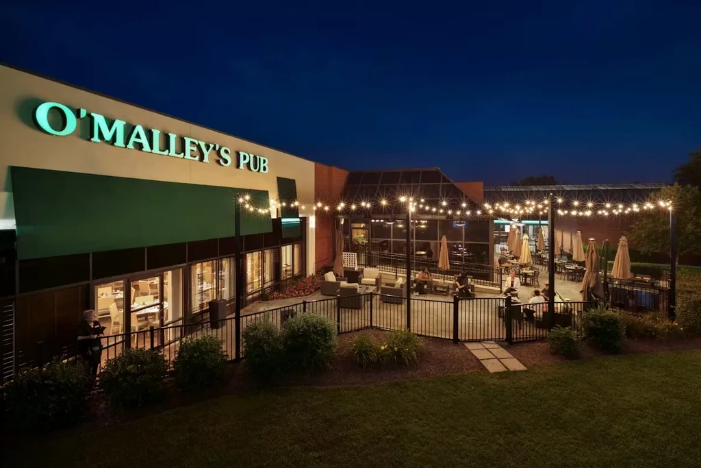O'Malley's Pub at night, extensive outdoor patio with string lights and people.