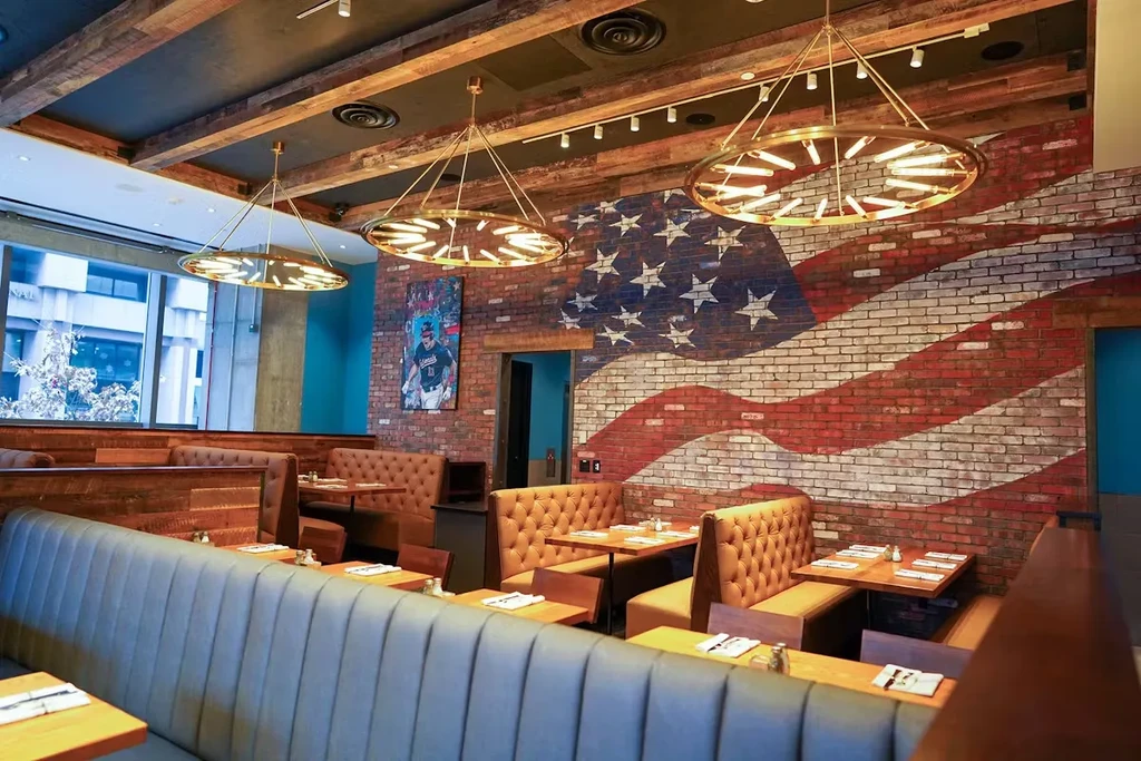 Restaurant interior with distressed American flag mural, teal wall, and wooden beams.