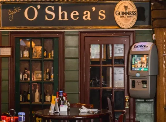 Interior of Jackie O' Shea's pub with bar, table, and jukebox.