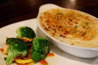 Close-up of a meal: baked casserole with browned top and colorful vegetables.