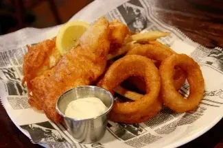 Classic fish and chips with onion rings, tartar, and lemon.